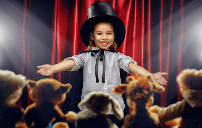niña realizando acto de magia a peluches